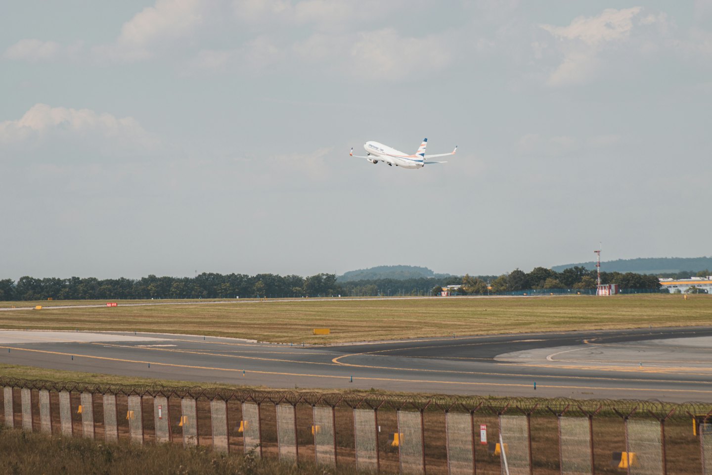 Airplane with blue and red markings takes off into a clear sky.