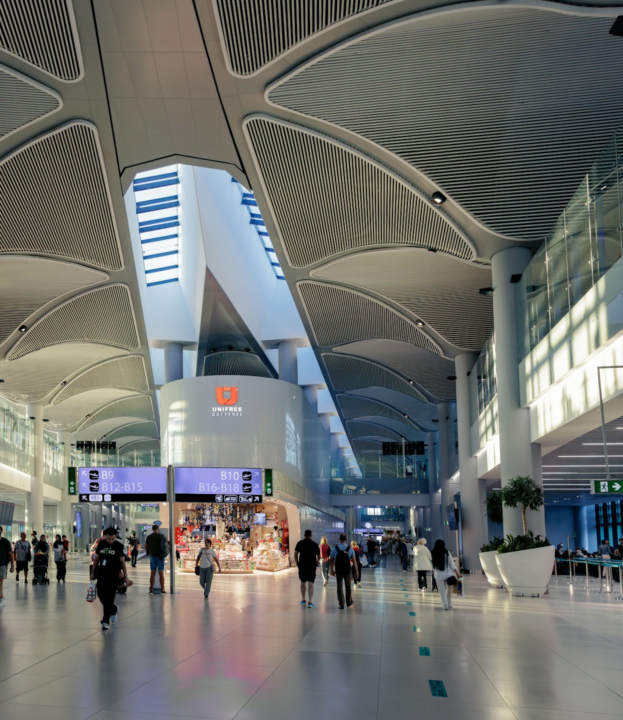 People walking through a spacious airport terminal with arched ceilings.