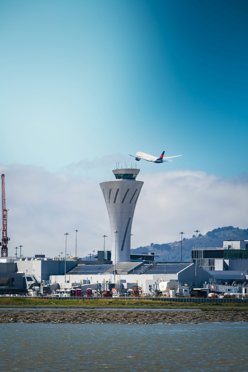 Airplane ascending past an air traffic control tower.