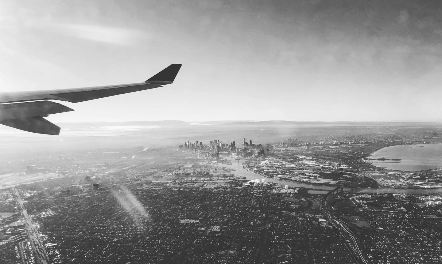 Airplane wing overlooking a sprawling city and river.