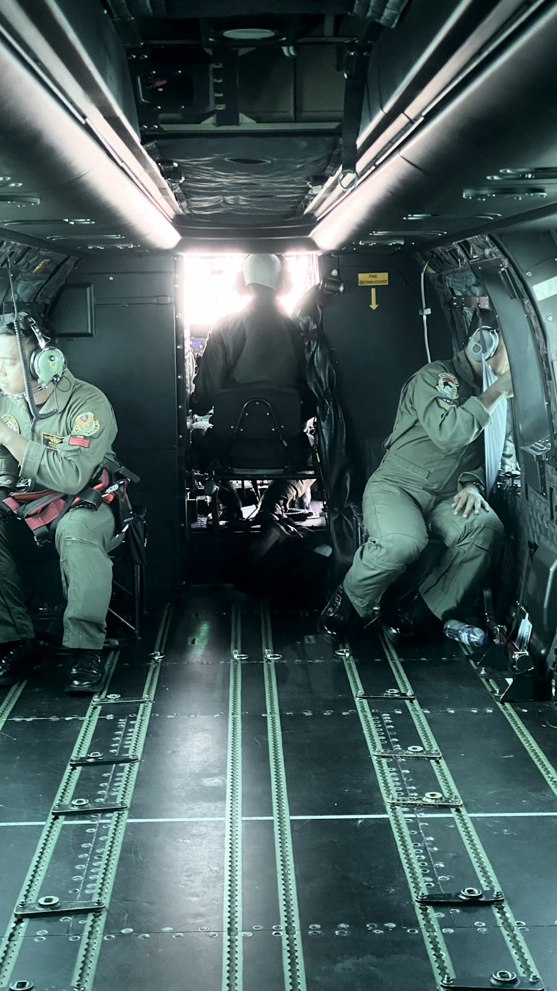 Three uniformed crew members sit inside a cargo aircraft.